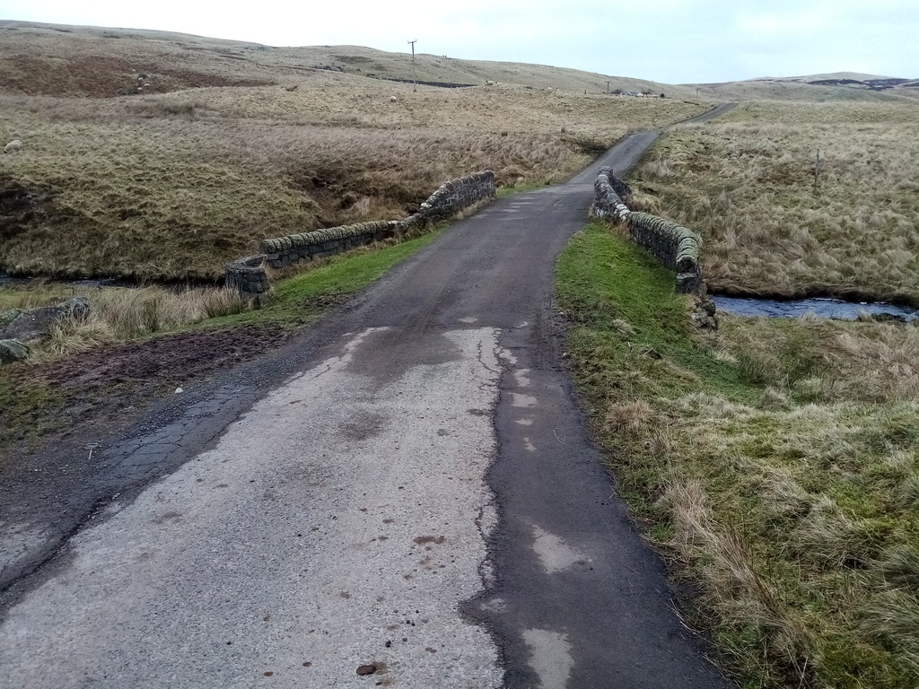 bridge with low wall over a small burn in sloping
     moorland