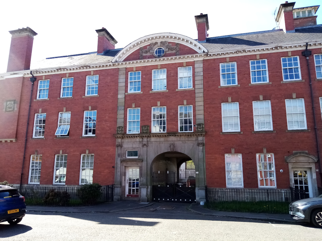 a building of red brick accentuated with grey stone,
     with a central stone archway