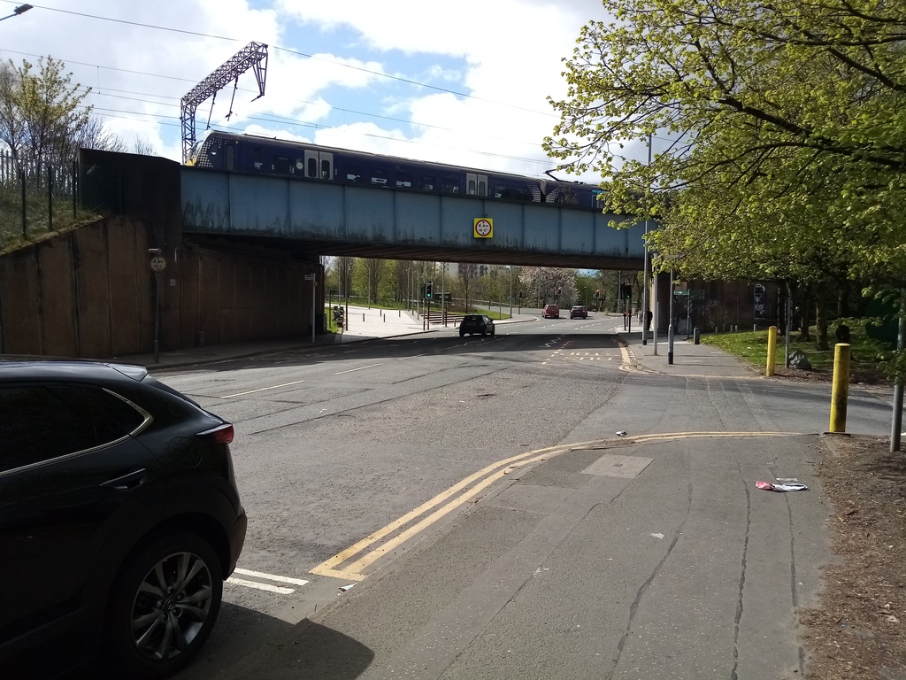 boxy metal railway bridge over a busy main road